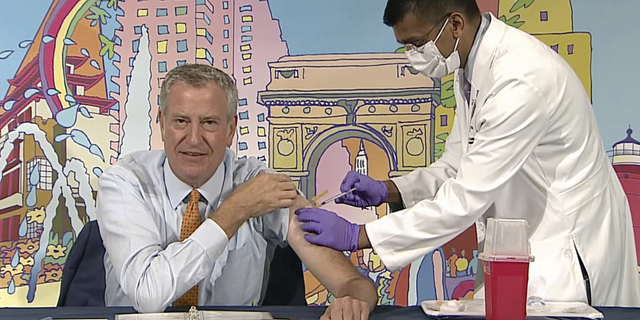 New York Mayor Bill de Blasio, left, receives a COVID-19 Moderna vaccine booster from New York City Health Commissioner Dr. Dave Chokshi.