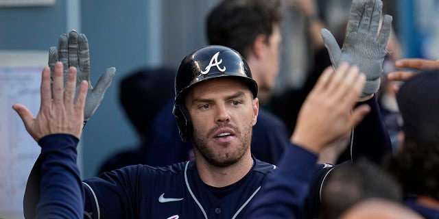 Atlanta Braves' Freddie Freeman is congratulated after hitting a two-run home run during the first inning against the Los Angeles Dodgers in Game 5 of baseball's National League Championship Series Thursday, Oct. 21, 2021, in Los Angeles.