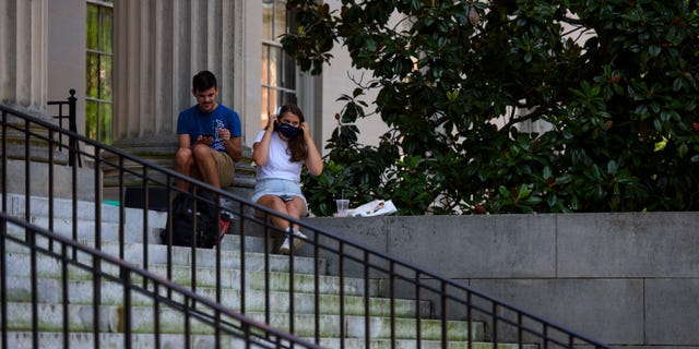 CHAPEL HILL, NC - 팔월 18: A person puts on a mask outside the closed Wilson Library at the campus of the University of North Carolina at Chapel Hill on August 18, 2020 in Chapel Hill, 노스 캐롤라이나. The school halted in-person classes and reverted back to online courses after a rise in the number of COVID-19 cases over the past week. (Photo by Melissa Sue Gerrits/Getty Images)