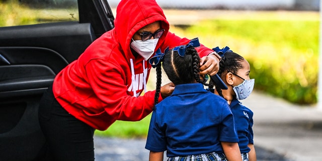 A mother adjusts the face mask of her child as she enters the St. Lawrence Catholic School on the first day of school after summer vacation in north of Miami, on Aug. 18, 2021. (Photo by CHANDAN KHANNA/AFP via Getty Images)