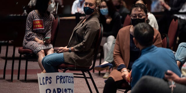 A woman sits with her sign during a Loudoun County Public Schools (LCPS) board meeting in Ashburn, Virginia on October 12, 2021. - Loudoun county school board meetings have become tense recently with parents clashing with board members over transgender issues, the teaching of critical race theory (CRT) and Covid-19 mandates. (Photo by ANDREW CABALLERO-REYNOLDS/AFP via Getty Images)