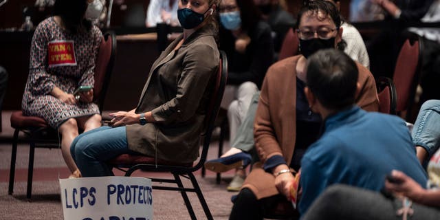 A woman sits with her sign during a Loudoun County Public Schools (LCPS) board meeting in Ashburn, Virginia, on Oct. 12, 2021. (Photo by ANDREW CABALLERO-REYNOLDS/AFP via Getty Images)