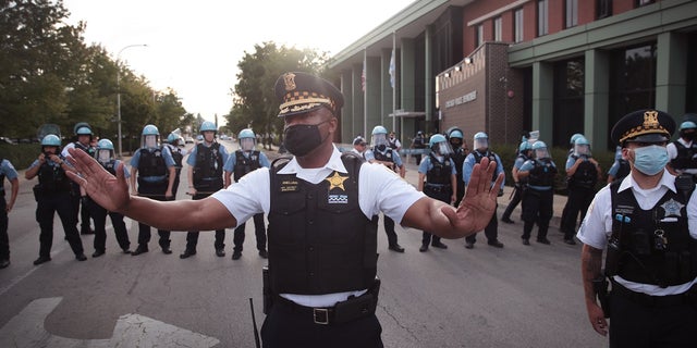 A Chicago police officer attempts to deescalate tension as Englewood residents clash with demonstrators protesting outside the 7th District station of the Chicago Police Department on August 11, 2020 in Chicago, Illinois. 