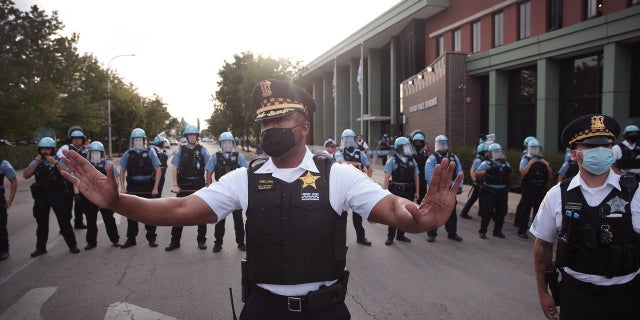 Chicago police officers try to defuse tensions as Inglewood residents clash with demonstrators outside the Chicago Police Department's District 7 Station on August 11, 2020 in Chicago, Illinois. 