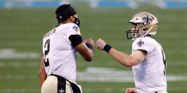 Drew Brees of the New Orleans Saints celebrates with teammate quarterback Jameis Winston following a touchdown pass against the Panthers on Jan. 3, 2021, in Charlotte, North Carolina.