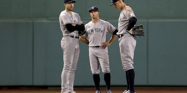 Joey Gallo #13, Brett Gardner #11 and Aaron Judge #99 of the New York Yankees stand in the outfield during a pitching change against the Boston Red Sox during the seventh inning of the American League Wild Card game at Fenway Park on October 05, 2021 in Boston, Massachusetts.