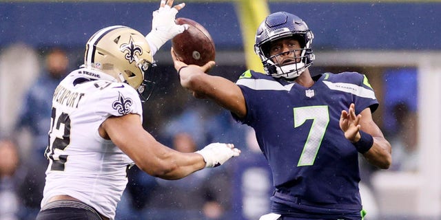 SEATTLE, WASHINGTON - OCTOBER 25: Geno Smith #7 of the Seattle Seahawks passes while pressured by Marcus Davenport #92 of the New Orleans Saints during the second quarter at Lumen Field on October 25, 2021 in Seattle, Washington. (Photo by Steph Chambers/Getty Images)