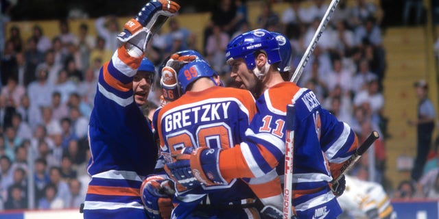 Jari Kurri #17 and Mark Messier #11 of the Edmonton Oilers congratulate teammate Wayne Gretzky #99 after scoring a goal during the 1988 Stanley Cup Final against the Boston Bruins in May 1988 at the Boston Garden in Boston.