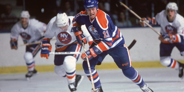 Canadian hockey player Mark Messier of the Edmonton Oilers skates with the puck as he is chased by three New York Rangers during a game against in the 1985 - 86 stagione.