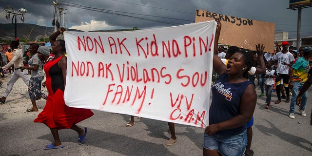 People demonstrate by carrying a banner with a message in Creole: "No to kidnappings, no to violence against women!  Long live the Ministries of Christian Aid,"  demanding the release of the kidnapped missionaries on Tuesday in Titanyen, north of Port-au-Prince, Haiti.