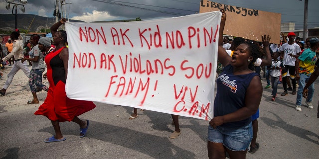 People protest carrying a banner with a message that reads in Creole: "No to kidnappings, no to violence against women ! Long live Christian Aid Ministries,"  demanding the release of kidnapped missionaries, in Titanyen, north of Port-au-Prince, Haiti on Tuesday.