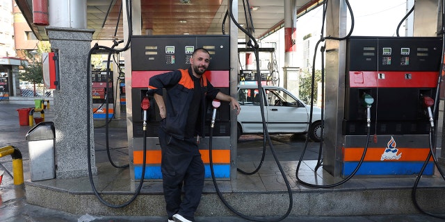 A worker leans against a gasoline pump that has been turned off at a gas station in Tehran, Iran on Oct. 26.