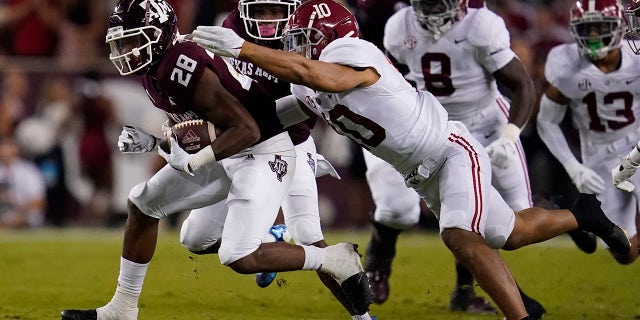 Le porteur de ballon Texas A&M Isaiah Spiller (28 ans) s'éloigne du secondeur de l'Alabama Henry To'oTo'o (10) pour un premier essai au cours du premier quart d'un match de football universitaire de la NCAA le samedi 9 octobre 2021 à Station universitaire, Texas. 