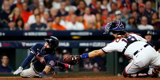 Dansby Swanson (7) of the Atlanta Braves slides safely into home ahead of the tag by Jason Castro (18) of the Houston Astros on a Freddie Freeman sacrifice fly in the eighth inning of Game 1 of the 2021 World Series at Minute Maid Park on Tuesday, October 26, 2021 in Houston.