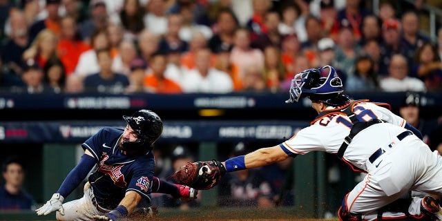 Dansby Swanson (7) of the Atlanta Braves slides safely into home ahead of the tag by Jason Castro (18) of the Houston Astros on a Freddie Freeman sacrifice fly in the eighth inning of Game 1 of the 2021 World Series at Minute Maid Park on Tuesday, October 26, 2021 in Houston.