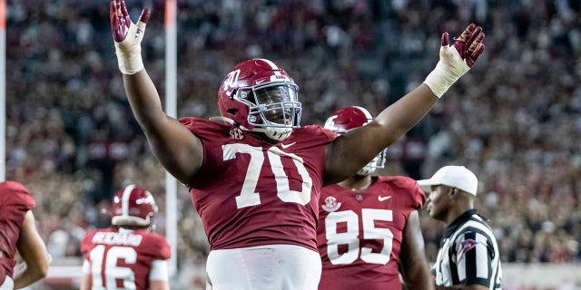 Alabama offensive lineman Javion Cohen (70) signals a touchdown after a dive into the end zone by quarterback Bryce Young.