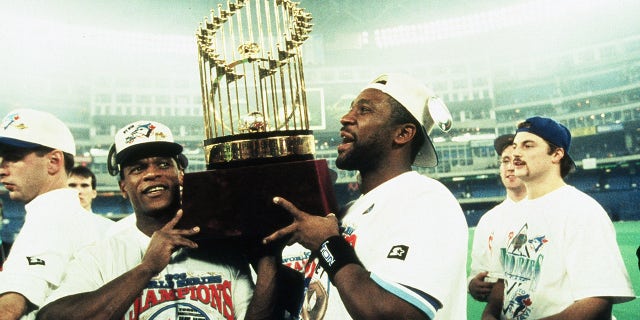 TORONTO, ON - OCTOBER 23: Rickey Henderson (L) and Joe Carter of the Toronto Blue Jays carry the World Series trophy after the Blue Jays victory during World Series game six between the Philadelphia Phillies and Toronto Blue Jays on October 23, 1993 at the Skydome in Toronto, Ontario, Canada. The Blue Jays defeated the Phillies 8-6.