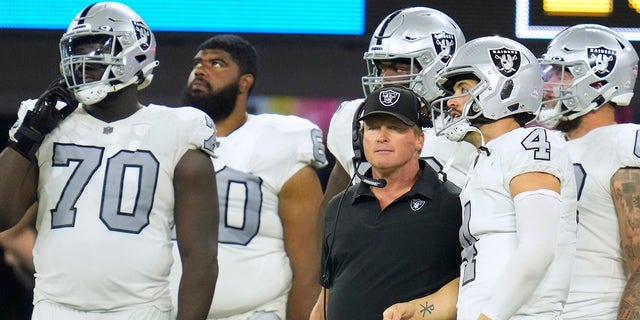 O técnico do Las Vegas Raiders, John Gruden, fala com o quarterback Derek Carr (4) durante o segundo tempo contra o Los Angeles Chargers no SoFi Stadium em Englewood, Califórnia.