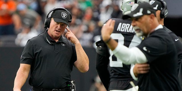 Las Vegas Raiders head coach Jon Gruden speaks on his helmet during the first half of an NFL football game against the Chicago Bears on Sunday, October 10, 2021, in Las Vegas.