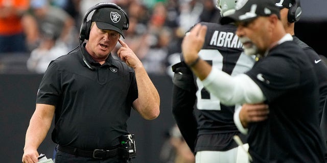 Las Vegas Raiders head coach Jon Gruden speaks on his helmet during the first half of an NFL football game against the Chicago Bears on Sunday, October 10, 2021, in Las Vegas.