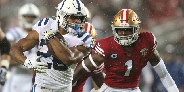 Le porteur de ballon des Colts d'Indianapolis Jonathan Taylor, à gauche, court devant le gardien libre des 49ers de San Francisco Jimmie Ward (1) pendant la première moitié d'un match de football de la NFL à Santa Clara, en Californie, le dimanche 24 octobre 2021.