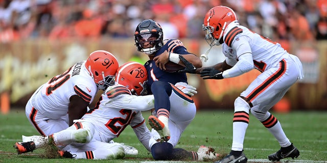 Chicago Bears quarterback Justin Fields slides for a short gain against Cleveland Browns defensive end Joe Jackson (91), linebacker Jeremiah Owusu-Koramoah (28) and cornerback Denzel Ward (21) during the second half of a game against the Cleveland Browns, Sunday, Sept. 26, 2021, in Cleveland.