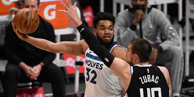 Karl-Anthony Towns #32 of the Minnesota Timberwolves looks to pass the ball as he is defended by Ivica Zubac #40 of the Los Angeles Clippers during the first half of the game at Staples Center on April 18, 2021 in Los Angeles, California.
