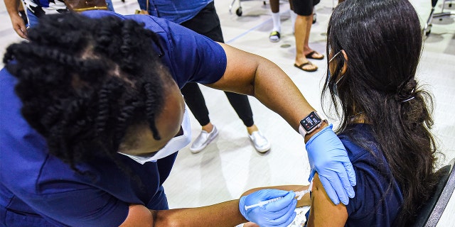 A nurse gives a girl a dose of the Pfizer vaccine at a COVID-19 vaccine clinic at a school. 