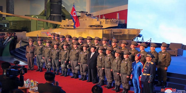 김정은 북한 국무위원장이 10일 북한 평양에서 열린 군비단체전시회 개막식에서 시범비행기를 조종한 전투기 조종사들과 단체사진을 찍고 있다.  (조선중앙통신/한국통신 AP를 통해)