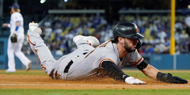 The San Francisco Giants' Kris Bryant slides safely into third base on a single by LaMonte Wade Jr. during the second inning of Game 4 of a baseball National League Division Series against the Los Angeles Dodgers, Tuesday, Oct. 12, 2021, in Los Angeles.