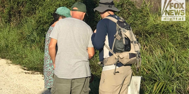 The Laundrie parents discuss their finds with a North Port Police detective shortly after investigators found their son's partial remains on Oct. 20, 2021. The parents also found a drybag, pictured in the detective's right hand, and other items.