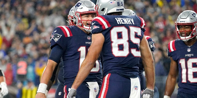 New England Patriots quarterback Mac Jones, left, celebrates after his touchdown pass to tight end Hunter Henry (85) during the first half of an NFL football game against the Tampa Bay Buccaneers, Sunday, Oct. 3, 2021, in Foxborough, Mass.