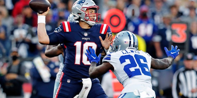 Il quarterback dei New England Patriots Mac Jones (10) lancia il cornerback dei Dallas Cowboys Jordan Lewis (26) nel primo tempo domenica 17 ottobre 2021, a Foxborough, Massachusetts.