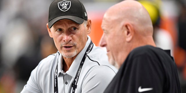 General manager Mike Mayock of the Las Vegas Raiders speaks to offensive line coach Tom Cable before a preseason game against the Seattle Seahawks at Allegiant Stadium on August 14, 2021 in Las Vegas, Nevada. The Raiders defeated the Seahawks 20-7.