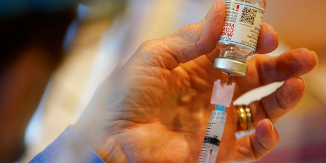 Pat Moore, with the Chester County, Pa., Health Department, fills a syringe with Moderna COVID-19 vaccine before administering it to emergency medical workers and healthcare personnel at the Chester County Government Services Center in West Chester, Pa. (AP Photo/Matt Slocum)