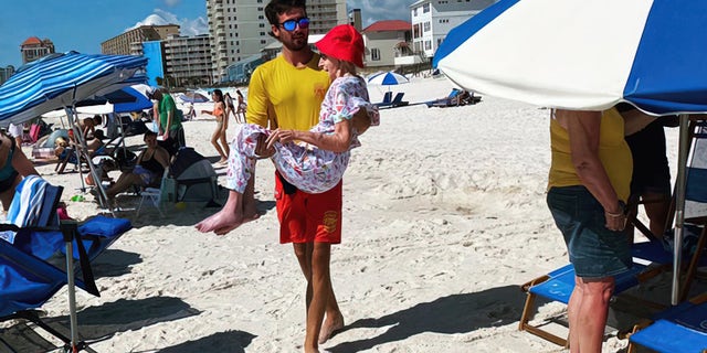 Lifeguards carry 95-year-old woman on beach