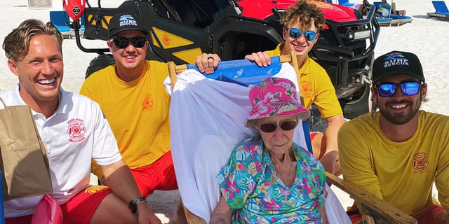 Lifeguards carry 95-year-old woman on beach