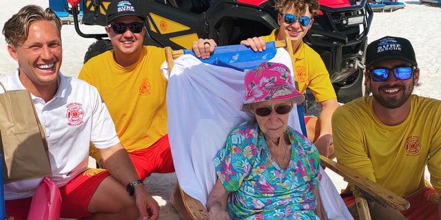 Lifeguards carry 95-year-old woman on beach