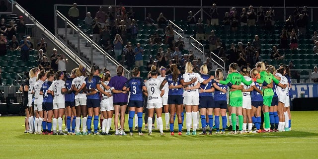 North Carolina Courage and Racing Louisville FC players pause and gather at midfield during the first half of an NWSL soccer match in Cary, N.C., Wednesday, Oct. 6, 2021.