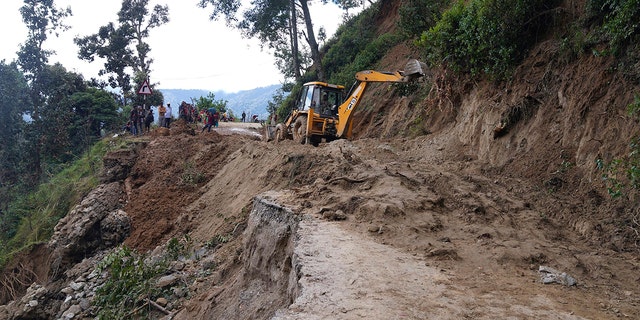 An earthmover helps clear a landslide-affected road after heavy rains in Dipayal Silgadhi, Nepal, Thursday.