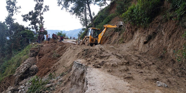 An earthmover helps clear a landslide-affected road after heavy rains in Dipayal Silgadhi, Nepal, Thursday.