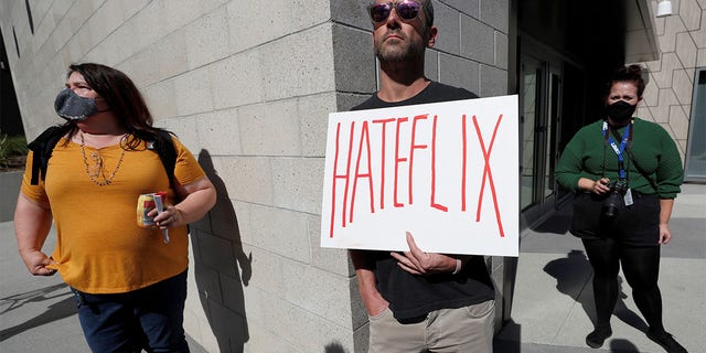 Dave Briggs holds a placard as he attends a rally in support of the Netflix transgender employee walkout ‘Stand Up in Solidarity’ to protest the streaming of comedian Dave Chappelle's new comedy special, in Los Angeles, California, U.S. October 20 2021. 