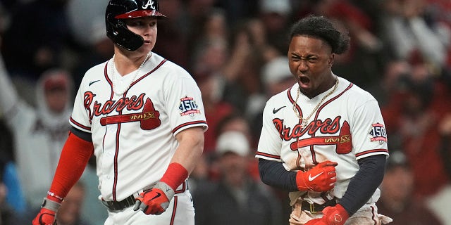 Atlanta Braves' Joc Pederson, left, looks on as Braves Ozzie Albies celebrates after scoring on a single by Austin Riley in the eighth inning in Game 2 of baseball's National League Championship Series Sunday, Oct. 17, 2021, in Atlanta.