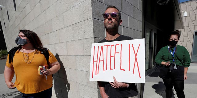 FILE PHOTO: A man holds a placard as he attends a rally in support of the Netflix transgender employee walkout "Stand Up in Solidarity" to protest the streaming of comedian Dave Chappelle's new comedy special, in Los Angeles, California, U.S. October 20 2021. REUTERS/Mario Anzuoni/File Photo