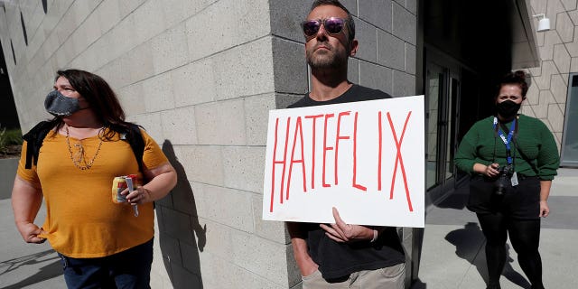 FILE PHOTO: A man holds a placard as he attends a rally in support of the Netflix transgender employee walkout "Stand Up in Solidarity" to protest the streaming of comedian Dave Chappelle's new comedy special, in Los Angeles, California, U.S. October 20 2021. REUTERS/Mario Anzuoni/File Photo