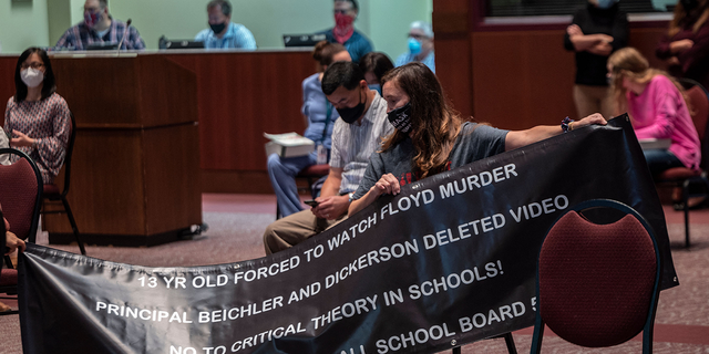 A woman holds up her sign against critical race theory being taught during a Loudoun County Public Schools board meeting in Ashburn, Virginia, on Oct. 12, 2021.