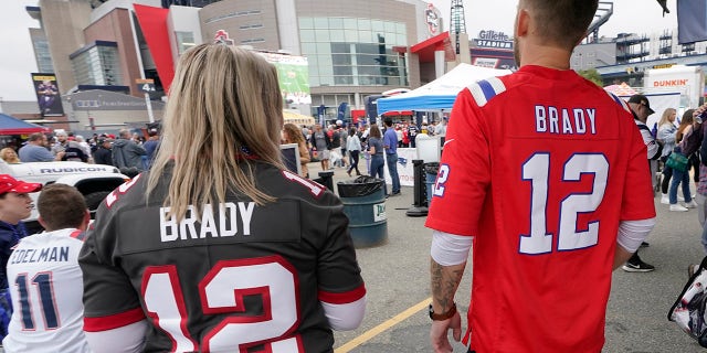 Melissa Zaske, left, of Vancouver, wears Tom Brady's Tampa Bay Buccaneers jersey while walking with her husband Derek, who wears Tom Brady's old New England Patriots jersey, prior to a game between the New England Patriots and Tampa Bay Buccaneers, Sunday, Oct. 3, 2021, in Foxborough, Mass.