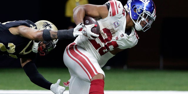 New York Giants running back Saquon Barkley (26) scores on a touchdown reception against New Orleans Saints cornerback Marshon Lattimore in the second half of an NFL football game in New Orleans, Sunday, Oct. 3, 2021.
