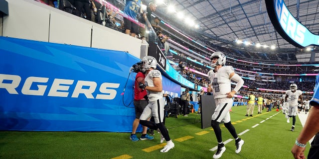 Las Vegas Raiders quarterback Derek Carr (4) and other players leave the field due to a weather delay shortly before the scheduled start an NFL football game against the Los Angeles Chargers, Monday, Oct. 4, 2021, in Inglewood, Calif.