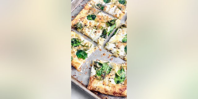 The pizza is topped with Alfredo sauce, fresh spinach, artichoke hearts, mozzarella and Parmesan. (Courtesy of Quiche My Grits)